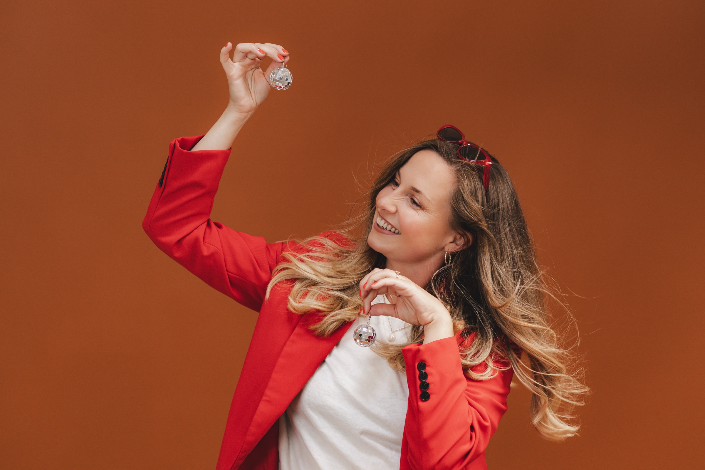 Jasmine holding disco-ball earrings against a warm terracotta backdrop
